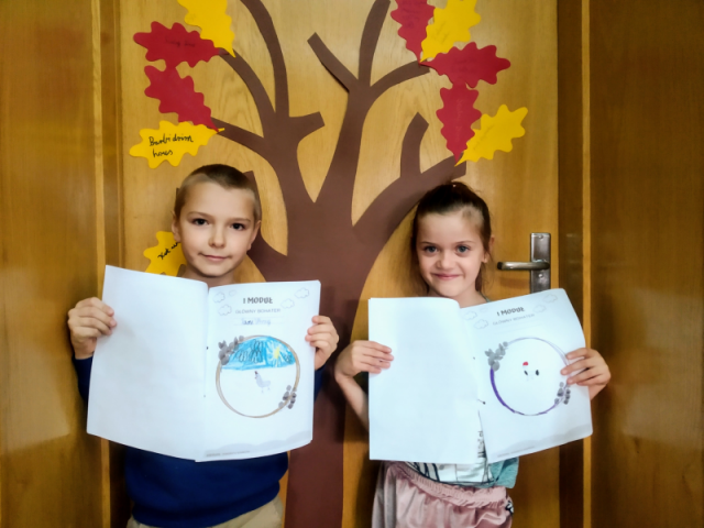Uczniowie stoją na tle klasowego drzewa czytelniczego i prezentują swoje rysunki w Lekturnikach