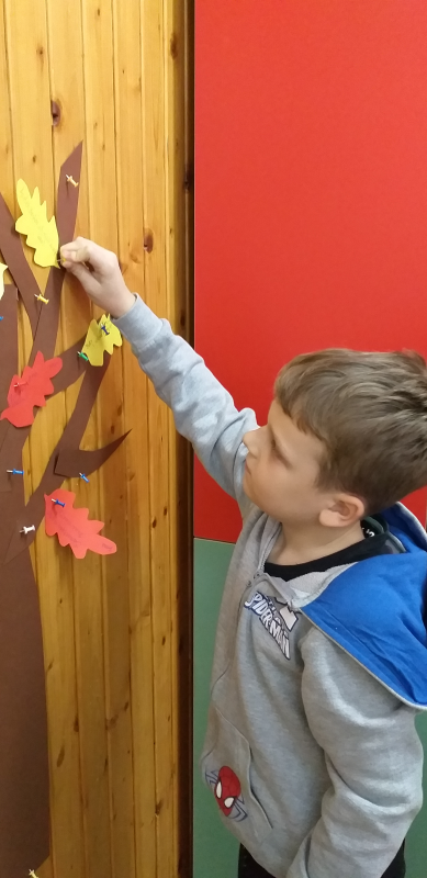 Chłopiec przypina listek do drzewa czytelniczego