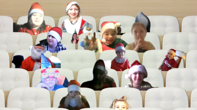 Uczniowie ubrani w mikołajkowe czapki siedzą podczas lekcji zdalnej na wirtualnej widowni