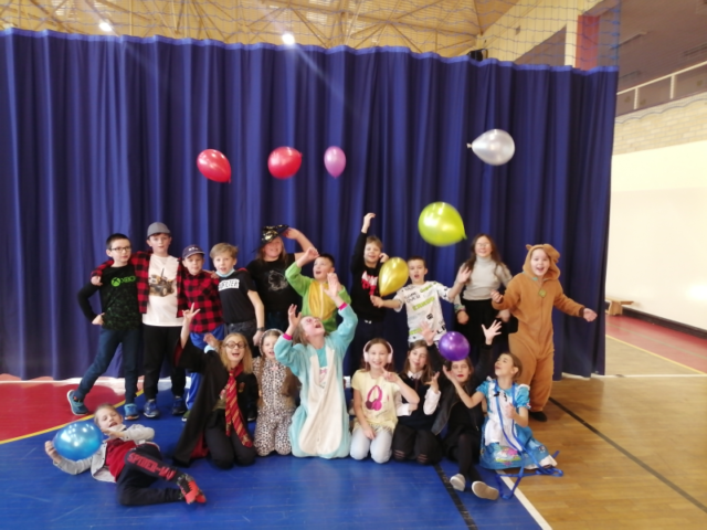 Karnawał w III b. Uczniowie   stoją w grupie i z radością podrzucają balony.
