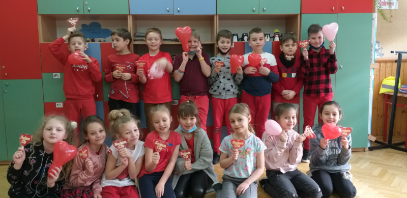Dzieci ubrane na czerwono trzymają balony i lizaki