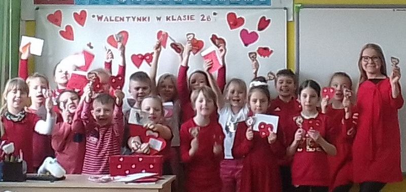 uczniowie klasy  2b wraz z wychowawczynią ubrani na czerwono z lizakami i walentynkami pozują w grupie, roześmiane buzie