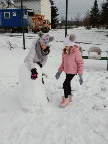Dziewczynki lepią bałwana ze śniegu