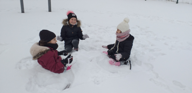 dziewczynki z 2b podczas zabawy w  zakopywanie w śniegu