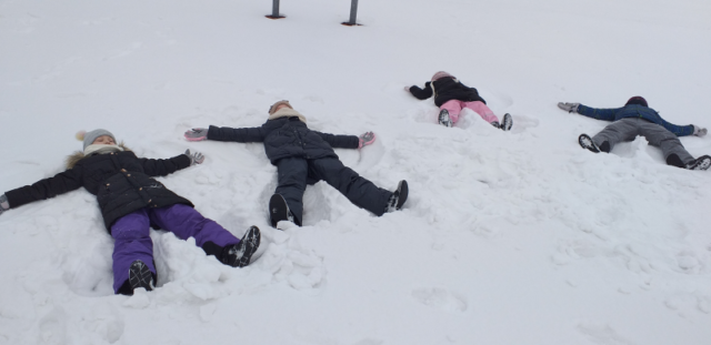 uczniowie z klasy 2b robią aniołki leżąc na śniegu
