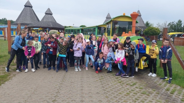 grupa dzieci pozuje do zdjęcia, w tle kolorowy pojazd - pociąg