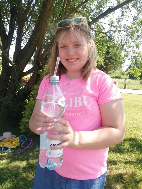 Dziewczynka stoi z butelką wody.