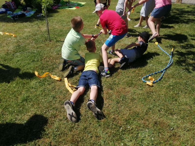 Chłopcy leżą na trawie i trzymają się liny.