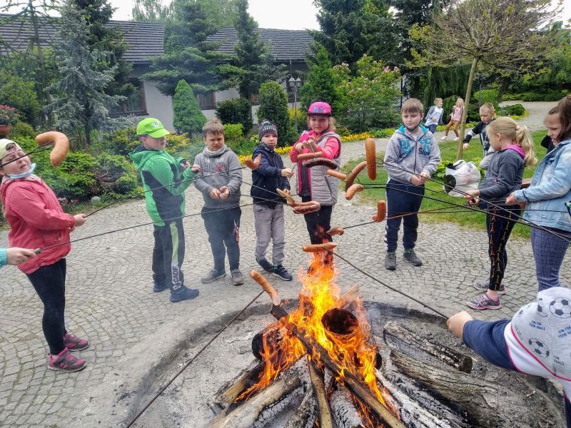Uczniowie pieką kiełbaski nad ogniskiem
