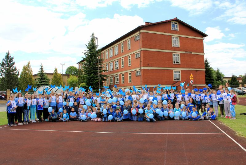 Uczestnicy akcji "Jesteśmy z Wami niebieskimi motylami" przed budynkiem szkoły