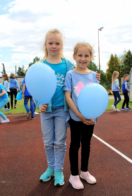 Dziewczynki w niebieskich strojach trzymają niebieskie baloniki