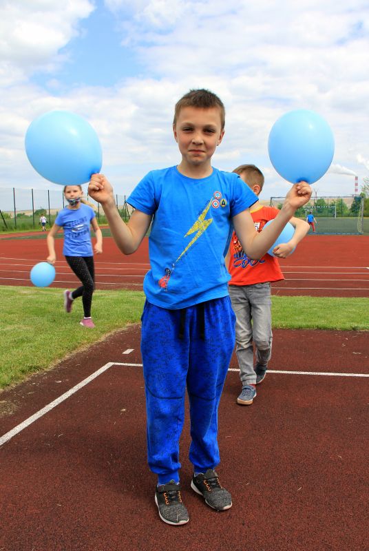 Chłopiec w niebieskim stroju trzyma niebieskie balony