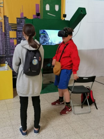 Chłopiec w okularach VR, obok stoi dziewczynka