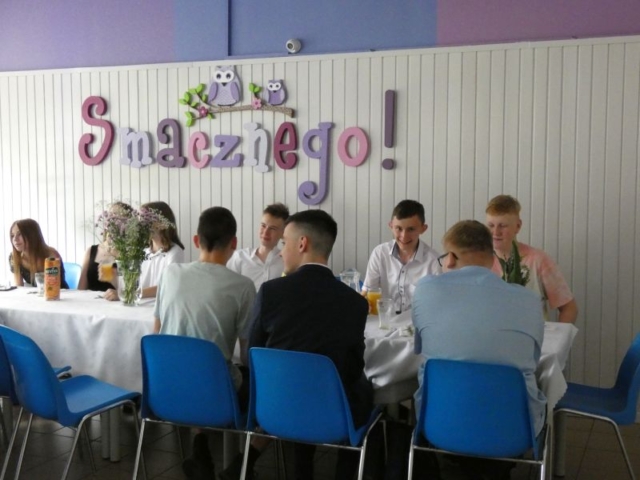 Uczniowie siedzą przy stole podczas poczęstunku