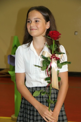 Uczennica stoi i trzyma różę