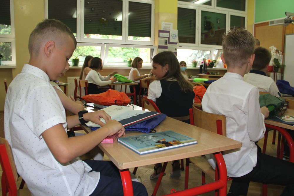 Uczniowie siedzą w klasie w ławeczkach