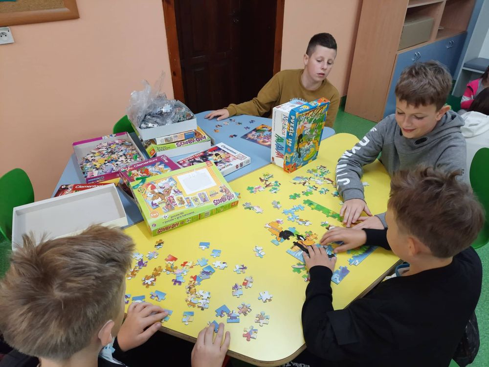 Grupa uczniów układa puzzle