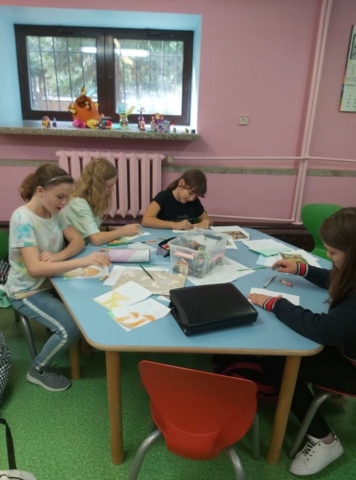 Grupa dziewczynek rysuje przy stoliku