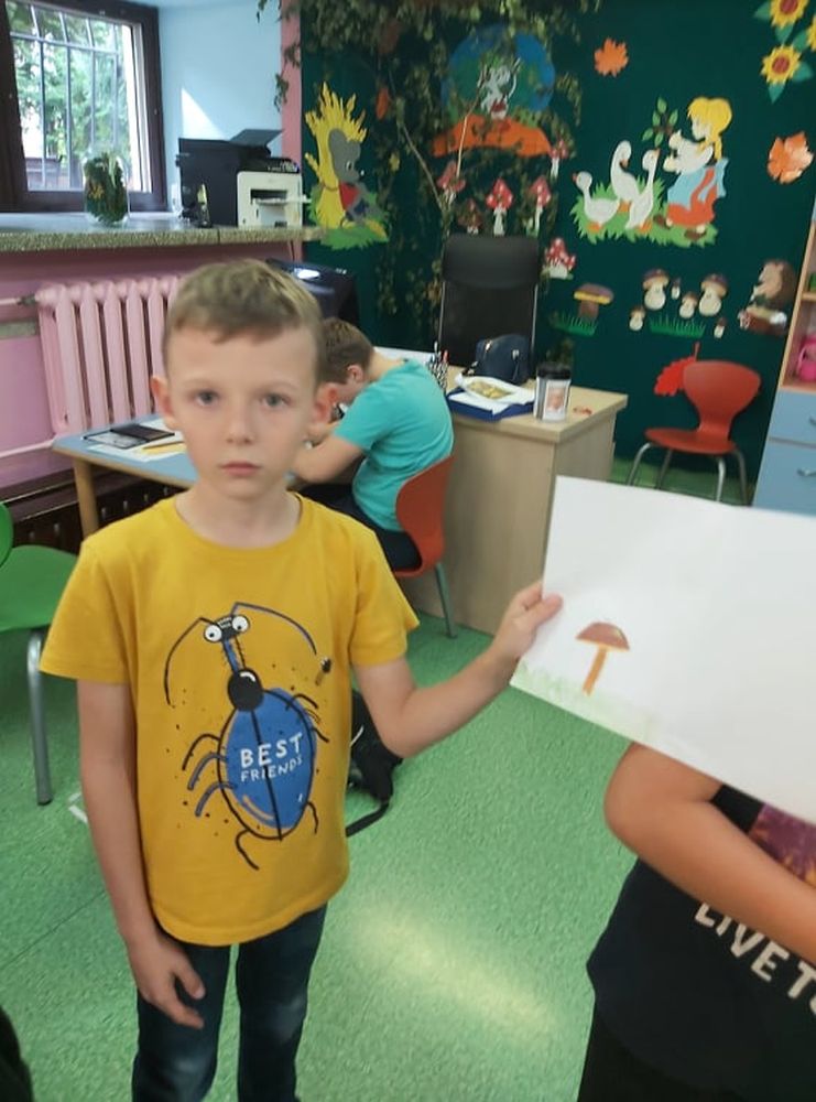 Chłopiec pokazuje swój rysunek z grzybem