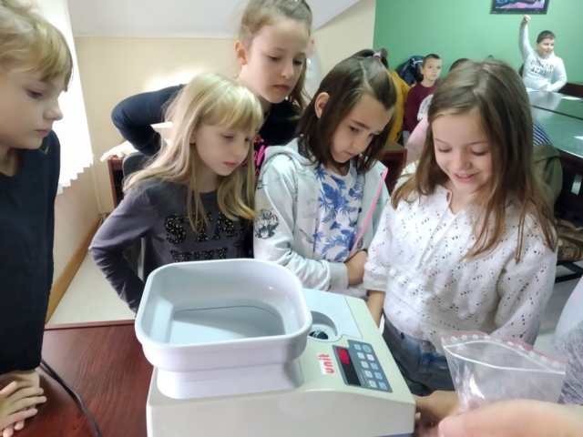 Dziewczynki oglądają maszynę do liczenia pieniędzy.