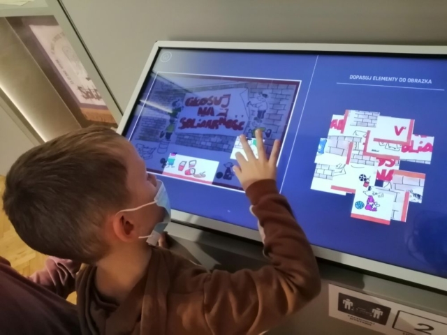 Uczeń układa puzzle na ekranie interaktywnym