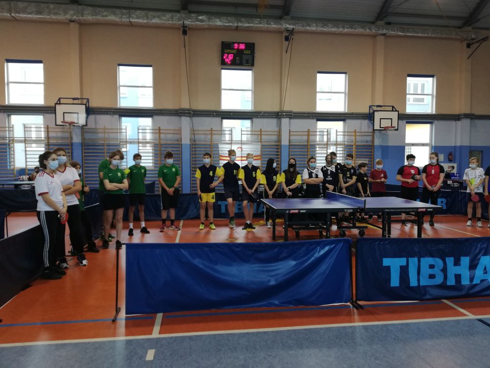 Reprezentacje szkół stoją wokół stołu do tenisa