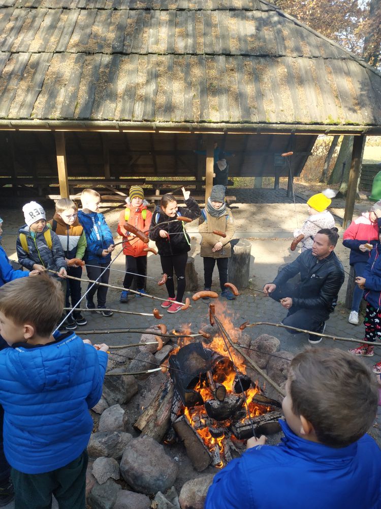 Dzieci pieką kiełbaski przy ognisku
