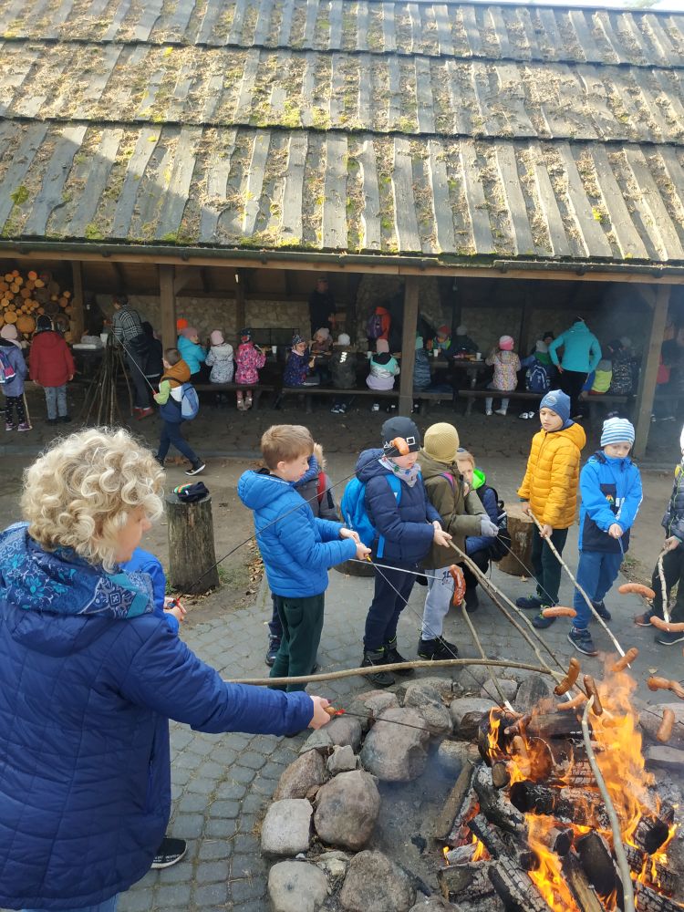 Dzieci pieką kiełbaski przy ognisku