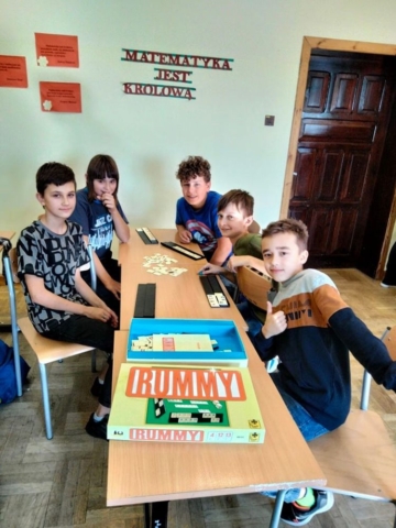 Grupa uczniów gra w grę planszową