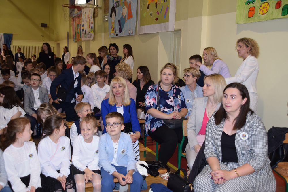 Społeczność szkolna i zaproszeni goście zgromadzeni na sali gimnastycznej oczekują na rozpoczęcie uroczystości
