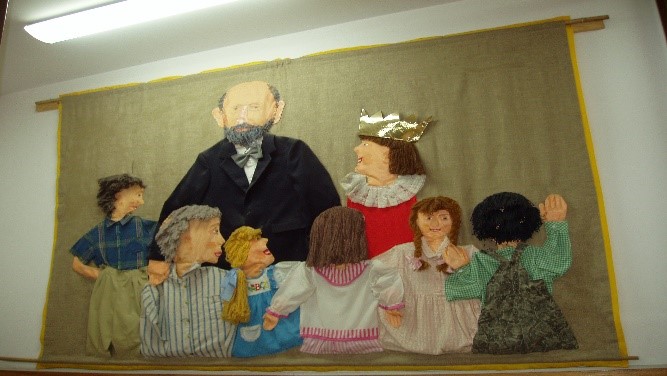 Okolicznościowy gobelin przedstawiający postać Janusza Korczaka, dzieci oraz Króla Maciusia Pierwszego.