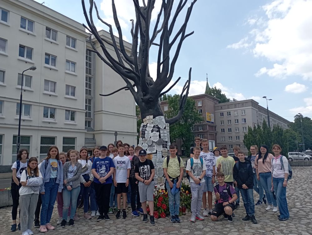 Grupa uczniów stoi pod Pomnikiem Drzewa