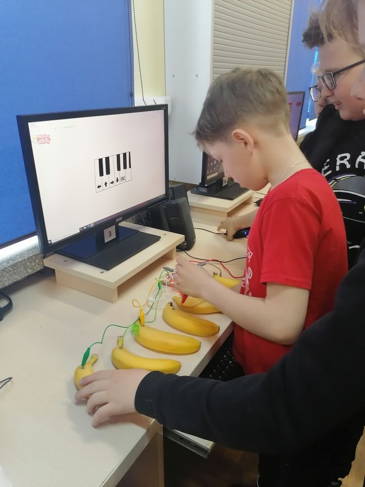 Uczniowie podłączają płytkę do owoców