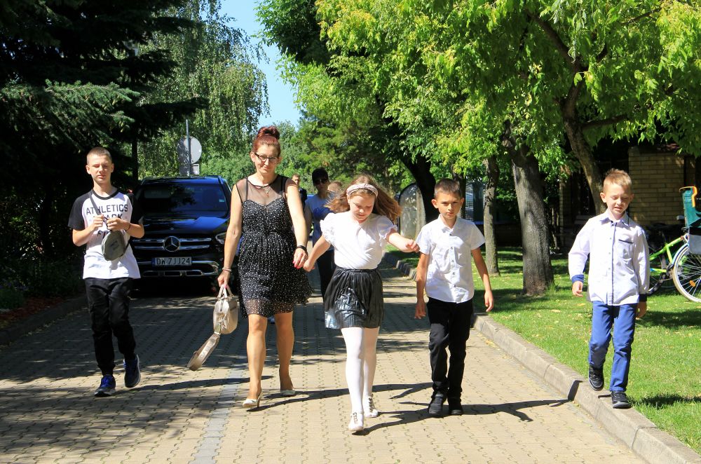 Uczniowie i rodzice idą na uroczystość zakończenia roku szkolnego