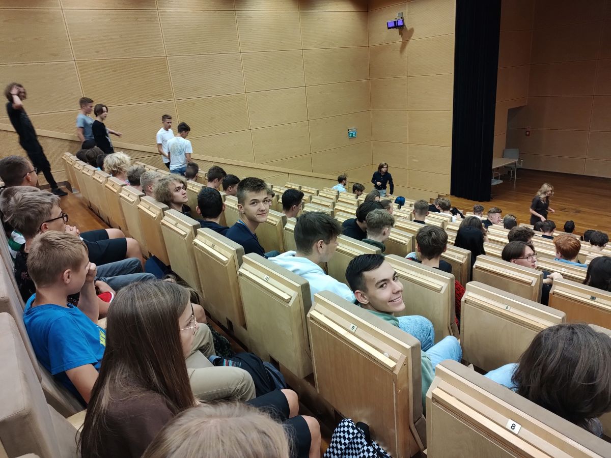 Grupa uczniów siedzi na auli