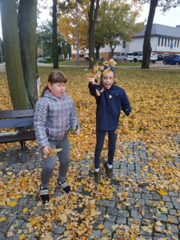 Dziewczynki rozrzucają jesienne liście
