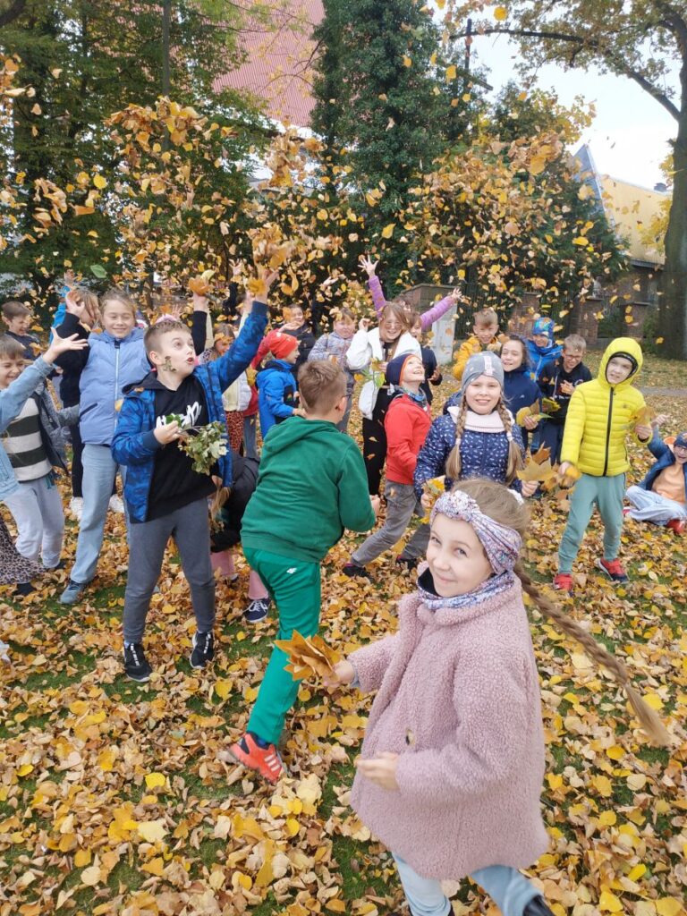 Dzieci rozrzucają kolorowe liście