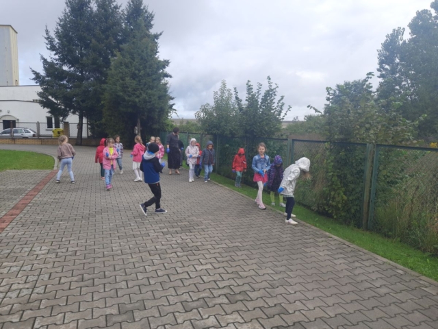 dzieci z wychowawczynią zbierają śmieci wokół szkoły