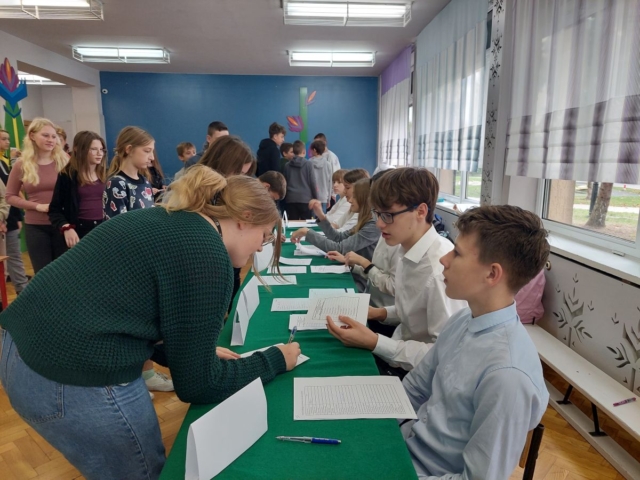 Uczniowie podpisują listę potwierdzającą pobranie karty wyborczej
