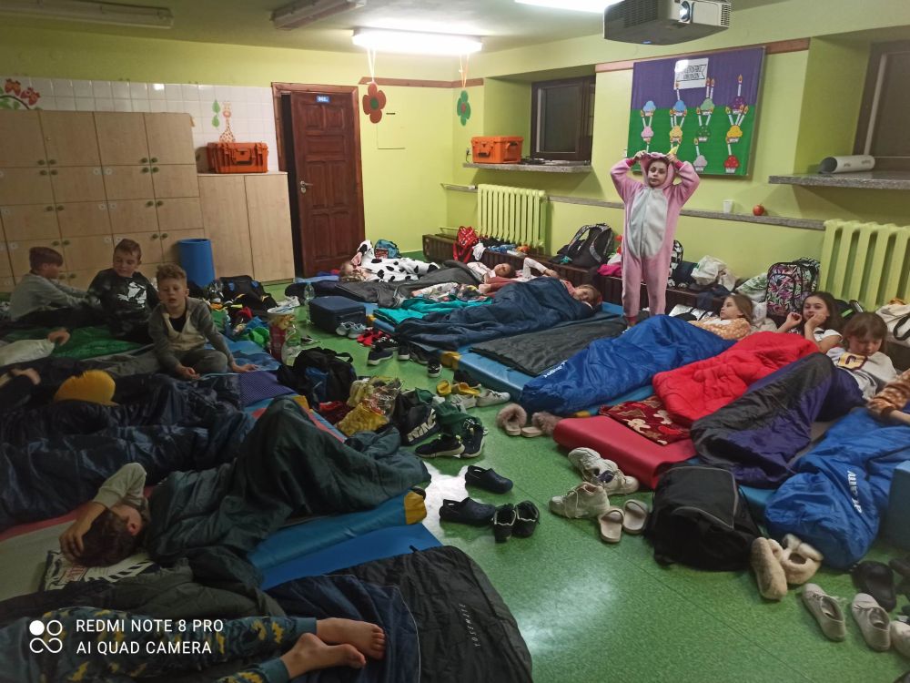Uczniowie leżą na materacach w śpiworach