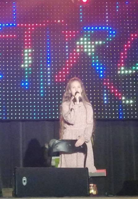 Dziewczynka stoi na scenie i śpiewa