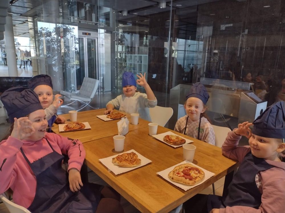 Dzieci jedzą upieczoną pizzę