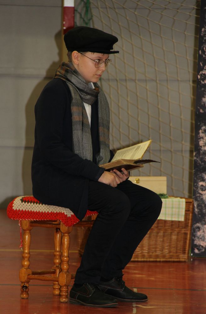 Chłopiec w stroju poety siedzi z książką w ręku