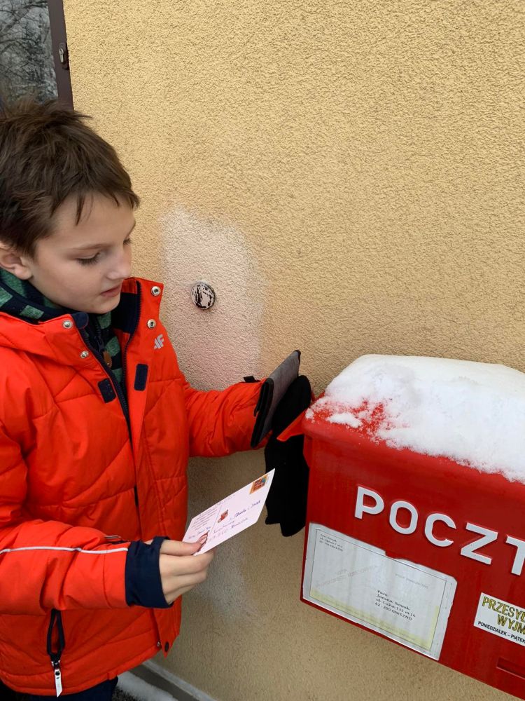 Chłopiec wrzuca kartkę do skrzynki pocztowej