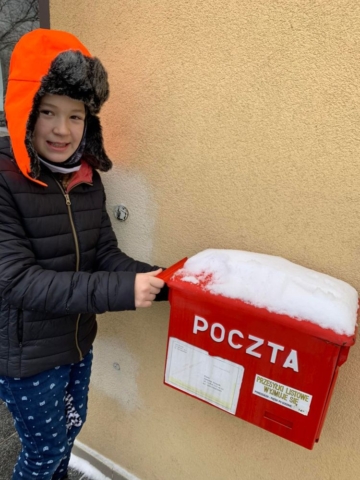 Dziewczynka wrzuca kartkę do skrzynko pocztowej