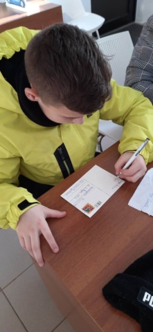 Chłopiec wypisuje kartkę pocztową