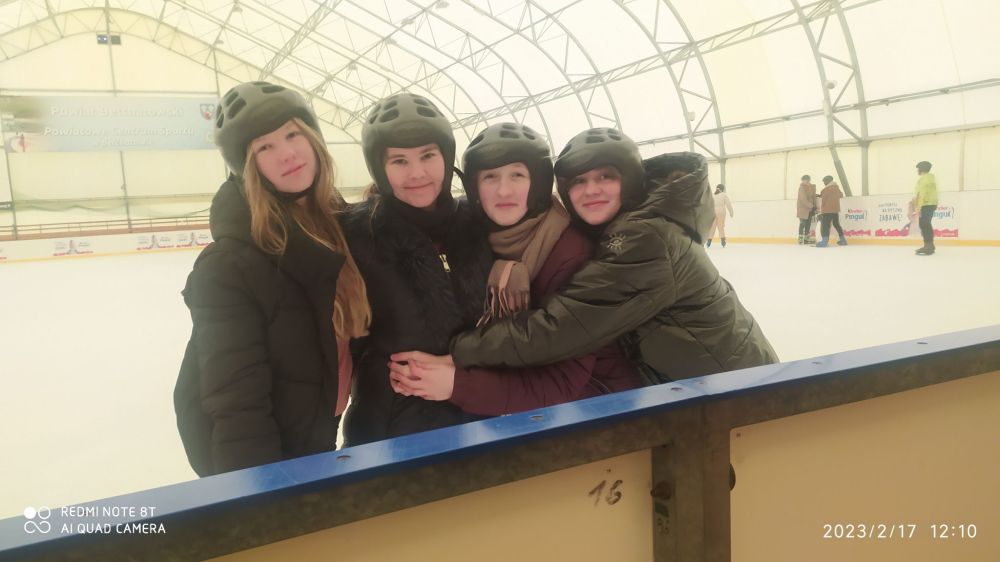 Cztery dziewczynki w kaskach stojące na lodowisku