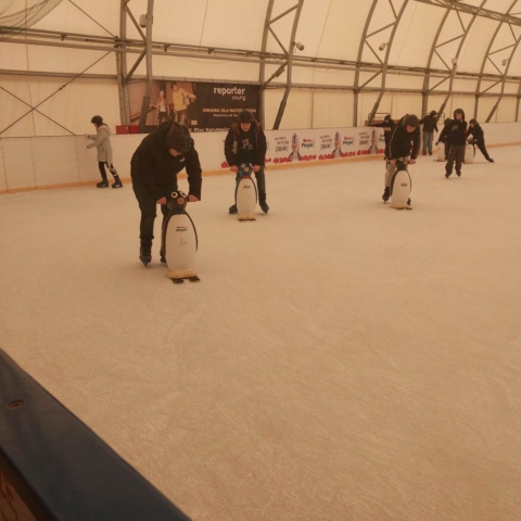 Uczniowie uczący się jeździć po lodzie z pomocą pingwinków