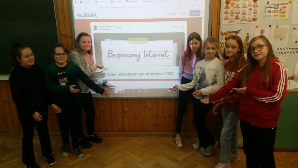 Grupa dziewczynek stoi przy tablicy multimedialnej