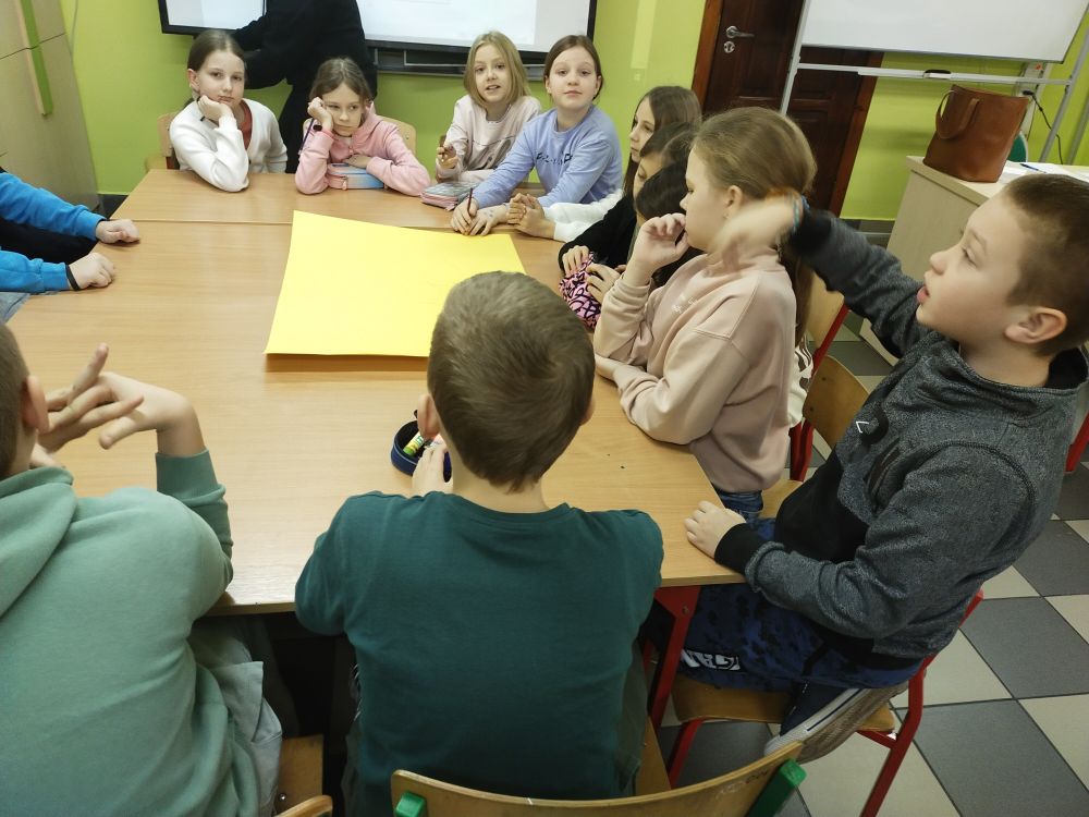 Uczniowie siedzą przy stole, rozmawiają